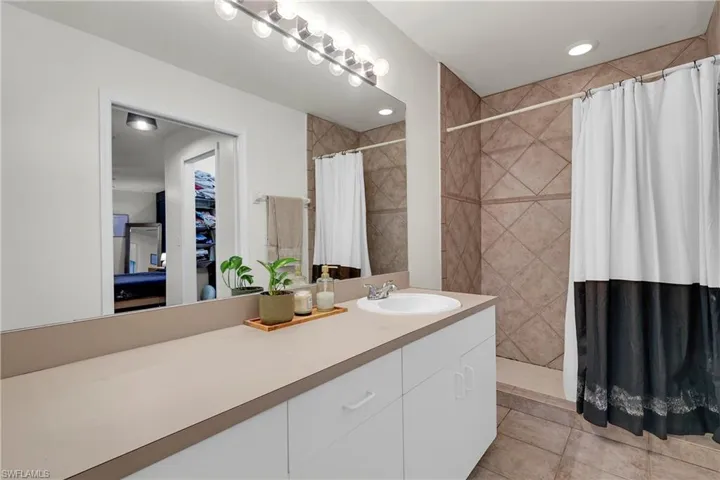 Featuring a walk-in stall shower, vanity, and light tile patterned shower walls