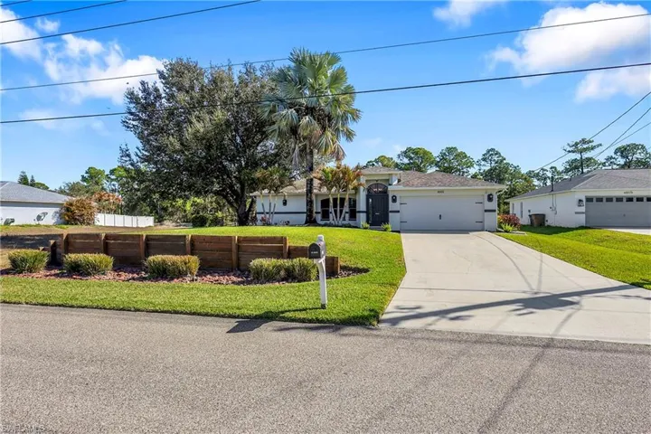 Ranch-style house with a front lawn, driveway, and an attached garage