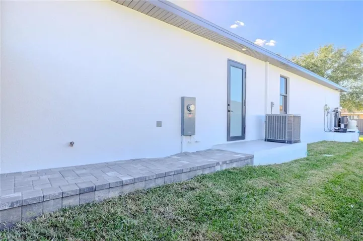 Rear view of property featuring stucco siding, a lawn, and a patio