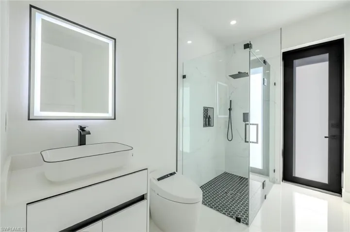 Bathroom featuring a marble finish shower, vanity, and recessed lighting