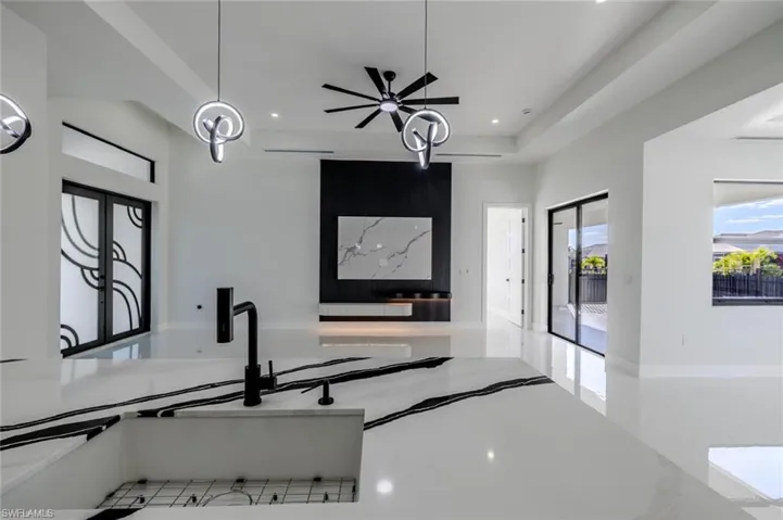 Kitchen with light stone countertops, hanging light fixtures, a tray ceiling, ceiling fan, and recessed lighting