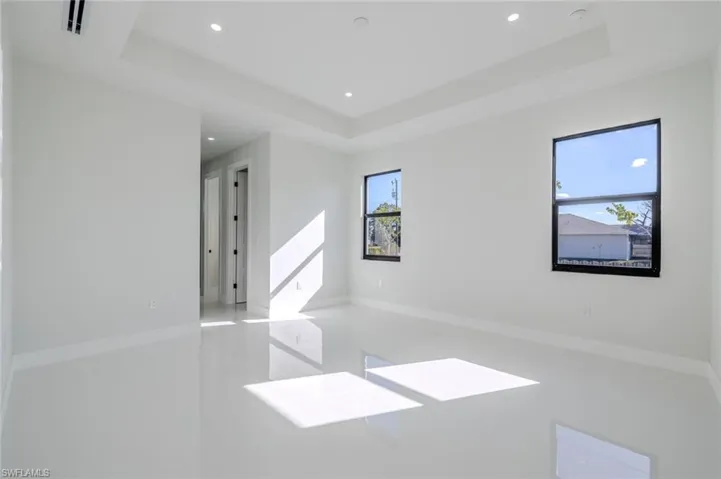 Unfurnished room with a tray ceiling, finished concrete floors, and recessed lighting