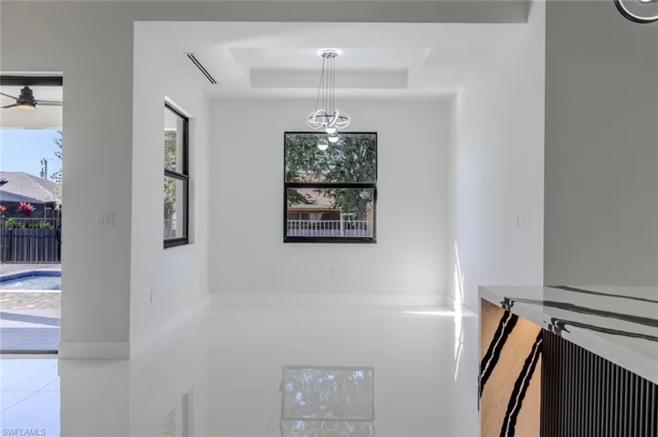 Unfurnished dining area with a tray ceiling, ceiling fan, and tile patterned flooring