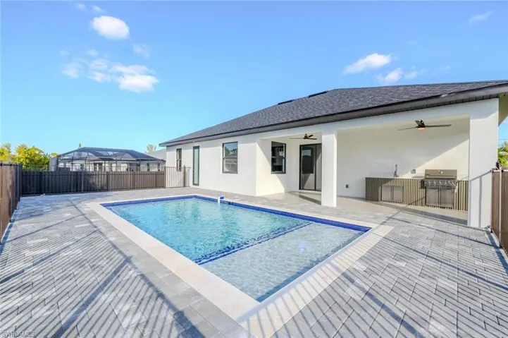 View of swimming pool featuring a patio area, a fenced backyard, and an outdoor kitchen