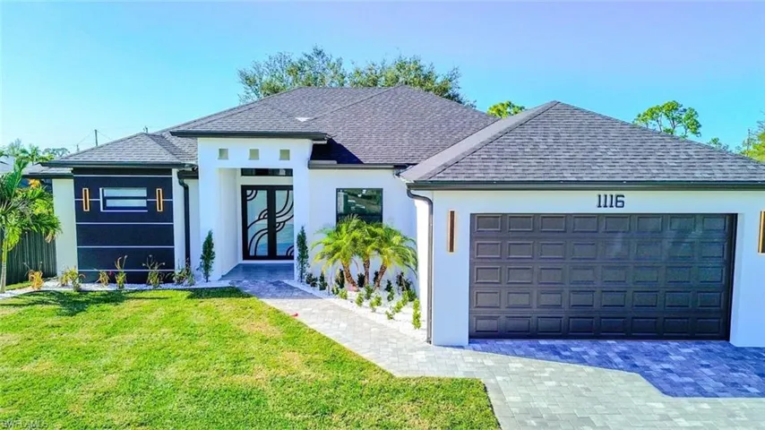 View of front facade featuring a shingled roof, stucco siding, a front yard, and an attached garage