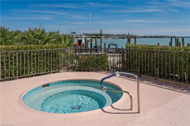 View of pool with a water view and a hot tub