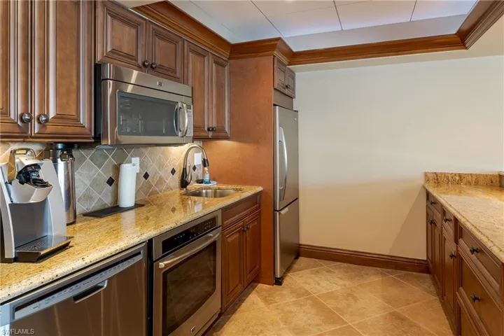 Kitchen with light stone countertops, appliances with stainless steel finishes, and a sink