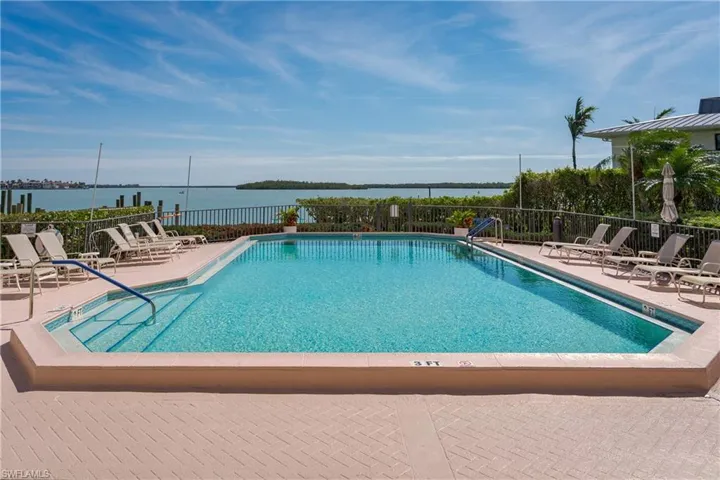 Pool with a water view, a patio, and fence