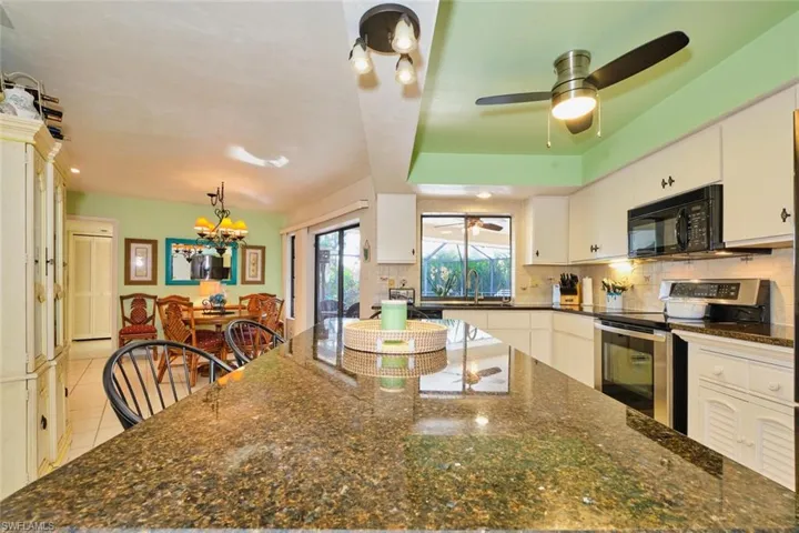 Long view of the kitchen overlooking the dining area.  Granite countertops and stainless steel appliances.  Slider to the lanai and open pass-through over the sink.  Nice that the sink overlooks the water.