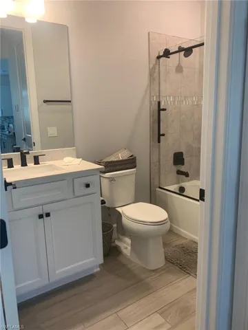 Bathroom with vanity, bath / shower combo with glass door, and light wood-style floors