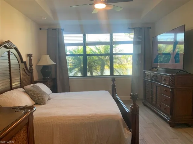 Bedroom featuring light wood-type flooring, a ceiling fan, and a tray ceiling