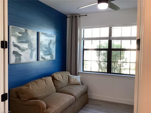 Sitting room featuring wooden walls, wood finished floors, and ceiling fan