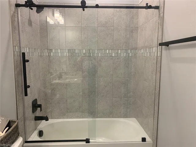 Bathroom featuring enclosed tub / shower combo and toilet