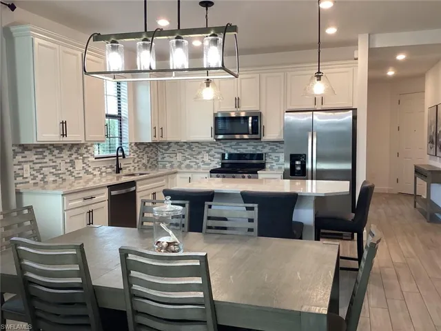 Kitchen featuring tasteful backsplash, decorative light fixtures, white cabinetry, light stone counters, and recessed lighting