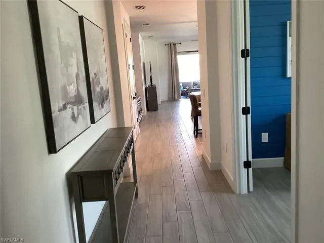 Corridor featuring light wood-style flooring and baseboards