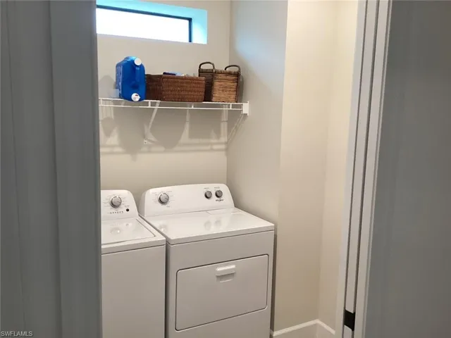 Laundry room with washer and clothes dryer and baseboards