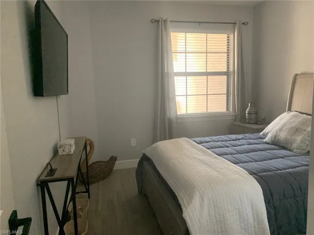 Bedroom featuring dark wood-style flooring and baseboards
