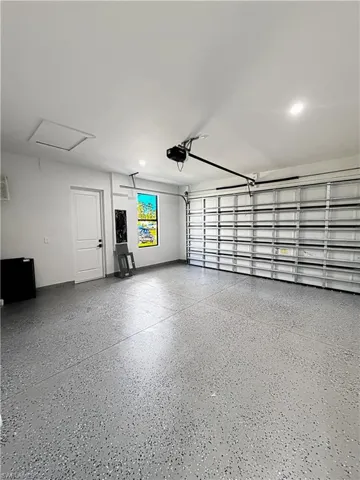 Spacious garage featuring a durable epoxy-coated floor, bright recessed lighting, a window for natural illumination, and an access door