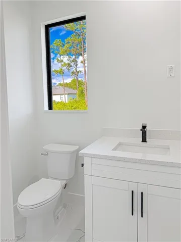 Modern bathroom featuring a white vanity with shaker-style cabinetry, a light speckled countertop, and a rectangular undermount sink with a matte black faucet