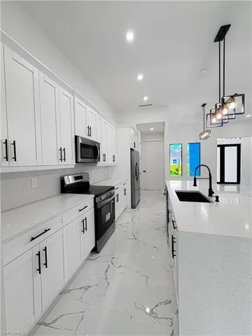 Modern kitchen featuring white shaker cabinetry with matte black hardware, stainless steel appliances, and light-toned countertops
