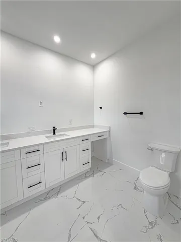 Modern bathroom featuring a white vanity with black hardware, an undermount sink, and a quartz countertop