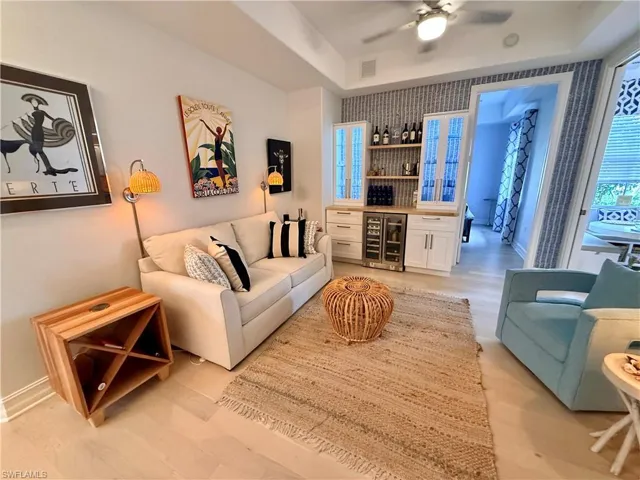 Living area with a dry bar, wine cooler, light wood finished floors, and a raised ceiling