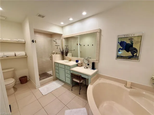 Full bath with light tile patterned flooring, vanity, a shower stall, a garden tub, and recessed lighting