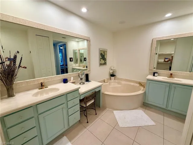 Bathroom featuring two vanities, light tile patterned flooring, a bath, a closet, and recessed lighting