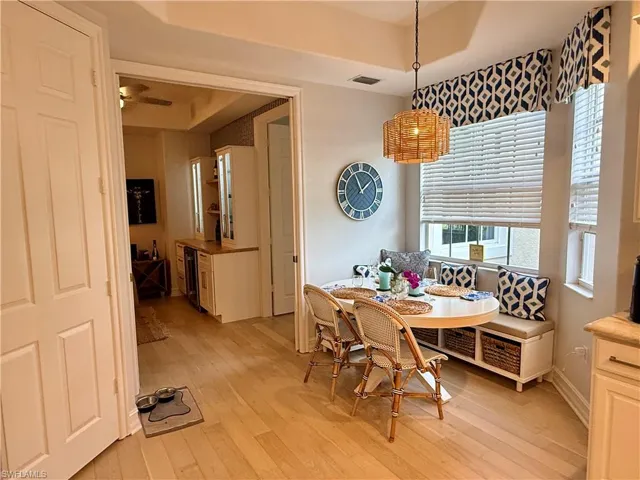 Dining area with light wood finished floors, breakfast area, a raised ceiling, and wine cooler