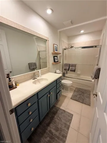 Bathroom with light tile patterned floors, vanity, combined bath / shower with glass door, and recessed lighting