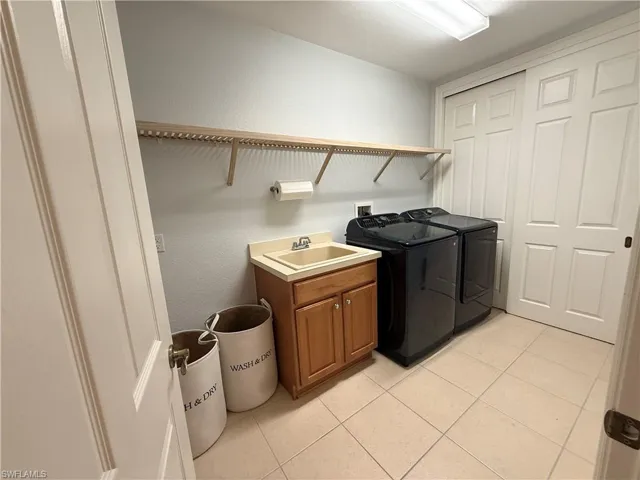 Laundry room featuring light tile patterned flooring, a textured wall, and washing machine and dryer