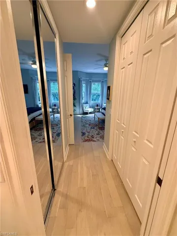 Hall with light wood finished floors and recessed lighting