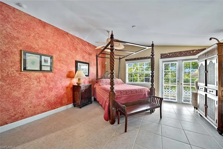 Bedroom with lofted ceiling, access to outside, ceiling fan, french doors, and light tile patterned floors