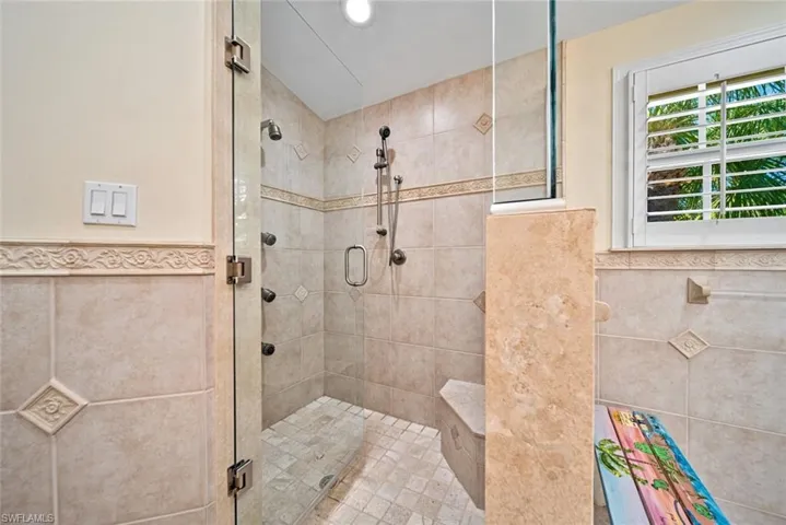 Bathroom with tile walls, a shower stall, and wainscoting