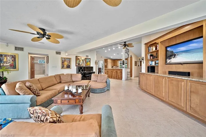 Living room featuring light tile patterned flooring, a ceiling fan, and vaulted ceiling