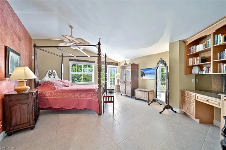 Bedroom featuring light tile patterned floors, lofted ceiling, and built in desk