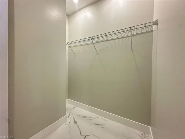 Walk in closet featuring marble finish flooring