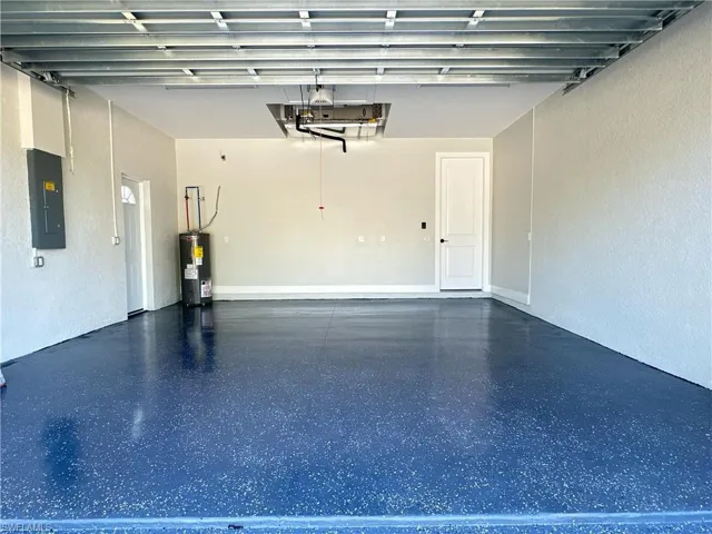 Garage with electric panel, a textured wall, and electric water heater