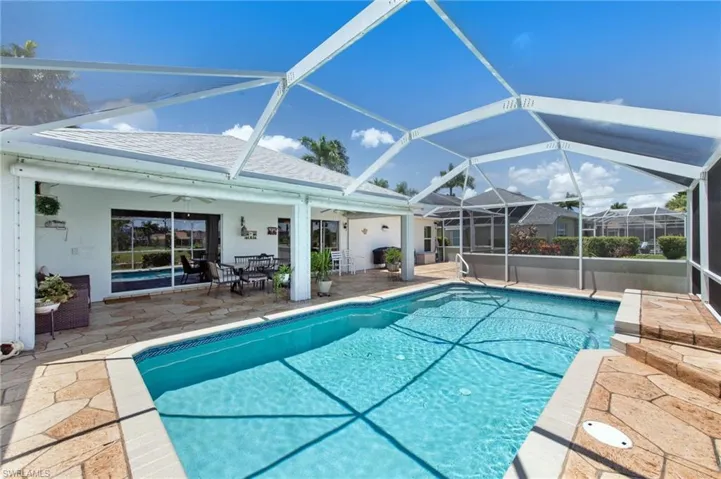 Outdoor pool featuring ceiling fan, a patio, outdoor dining space, and a lanai