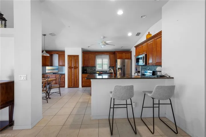 Kitchen featuring stainless steel appliances, a peninsula, recessed lighting, decorative backsplash, and a kitchen bar