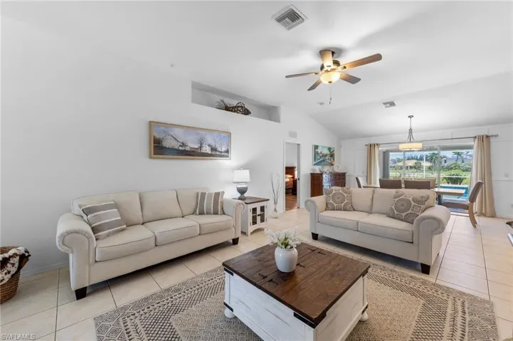 Living area with vaulted ceiling, light tile patterned floors, and ceiling fan