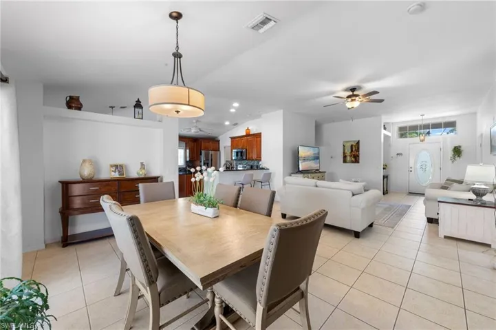 Dining space with light tile patterned flooring, plenty of natural light, a ceiling fan, and vaulted ceiling