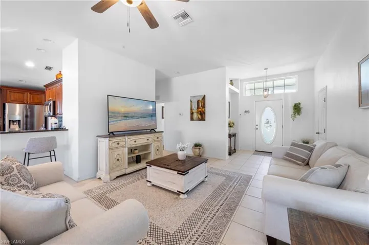 Living area featuring a ceiling fan, light tile patterned flooring, and recessed lighting