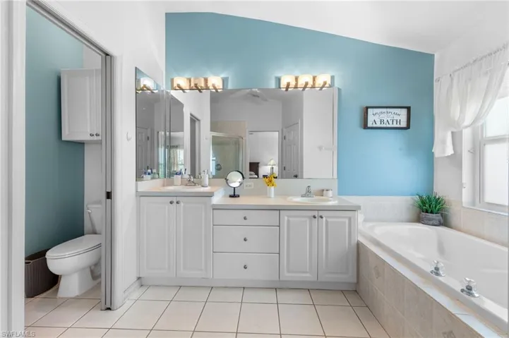 Full bath with double vanity, a garden tub, a shower stall, and tile patterned floors