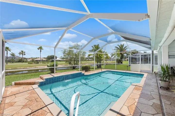 Swimming pool with a water view, a patio, and a lanai