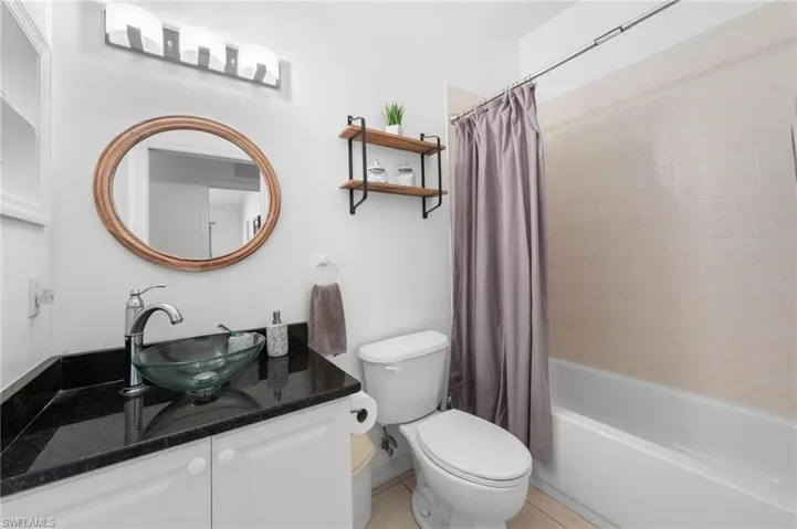 Bathroom featuring vanity, shower / tub combo with curtain, and tile patterned floors