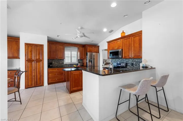 Kitchen featuring stainless steel appliances, a peninsula, tasteful backsplash, a ceiling fan, and recessed lighting