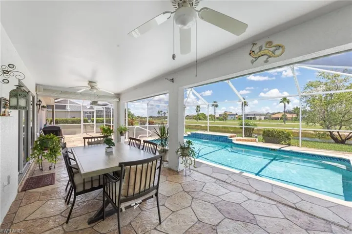 Outdoor pool with ceiling fan, a patio area, glass enclosure, and outdoor dining space