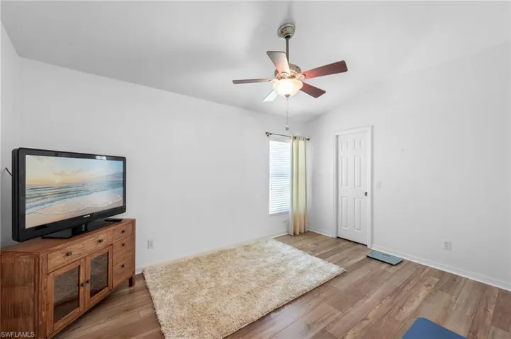 Unfurnished living room featuring light wood-style floors, a ceiling fan, and lofted ceiling