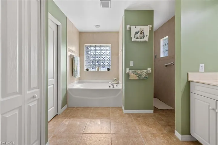 Bathroom featuring a healthy amount of sunlight, vanity, independent shower and bath, and tile patterned flooring